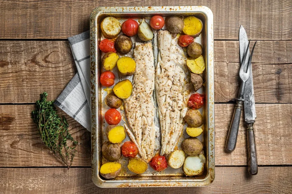 Hake fish fillet roasted fish meat with tomato and potato wooden background top view 1